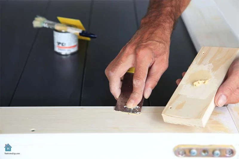 wood worker applying filler to the wood with putty knife